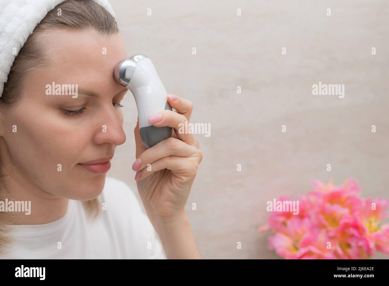 femme utilisant un appareil de signalisation faciale à micro-courant à la maison Banque D'Images
