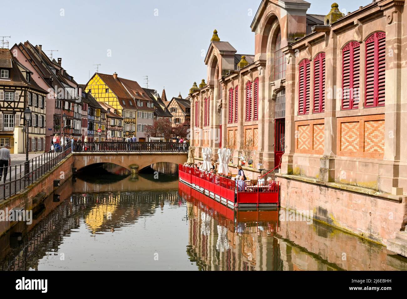 Colmar, France - avril 2022 : personnes assises aux tables d'un café sur un ponton flottant sur le canal à l'extérieur du bâtiment du marché Banque D'Images