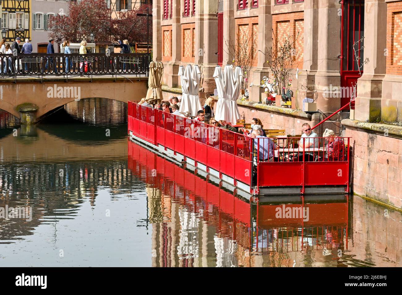 Colmar, France - avril 2022 : personnes assises aux tables d'un café sur un ponton flottant sur le canal à l'extérieur du bâtiment du marché Banque D'Images