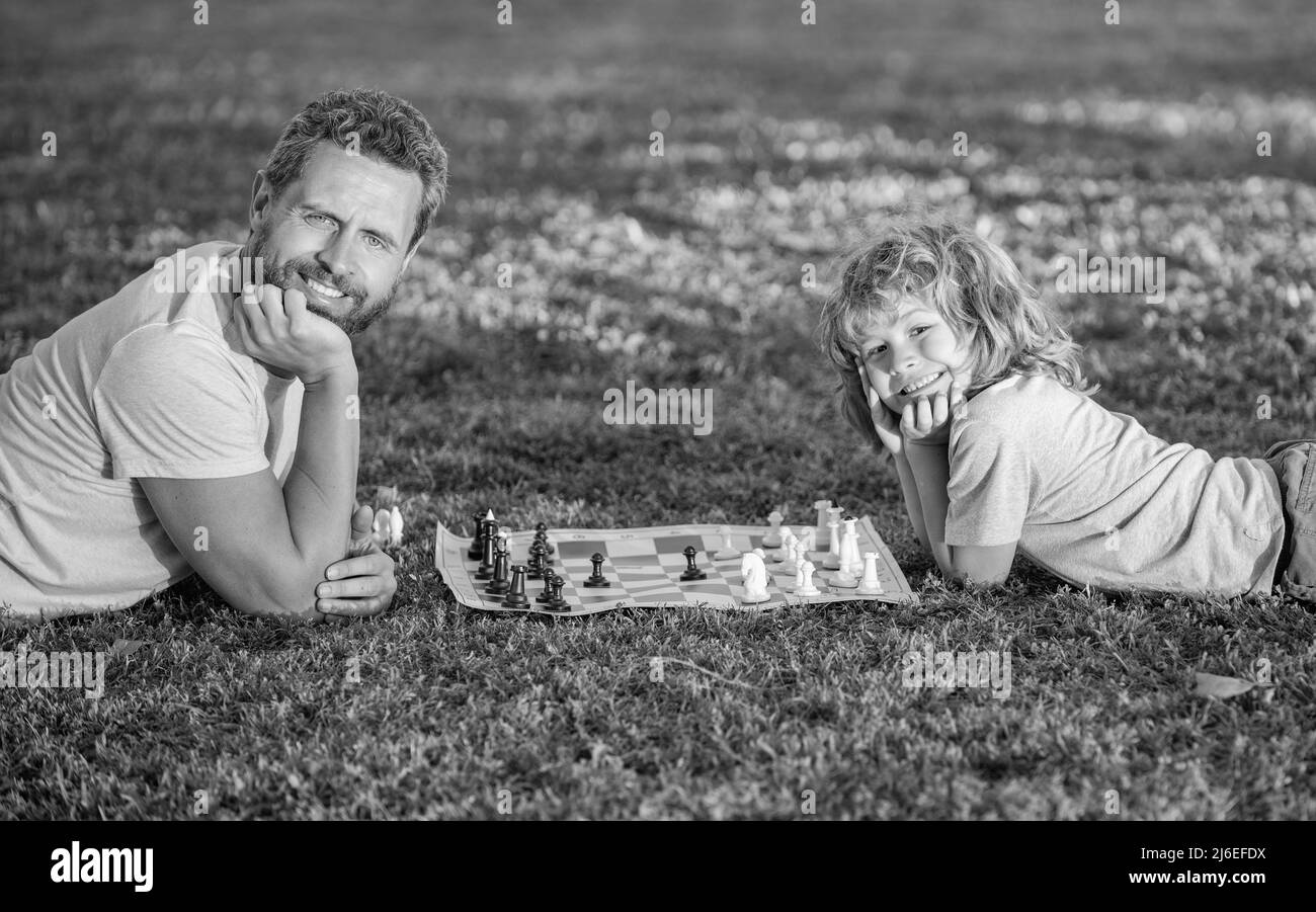 bonne famille de père homme et fils garçon jouant aux échecs sur l'herbe verte dans le parc en plein air, détendez-vous Banque D'Images