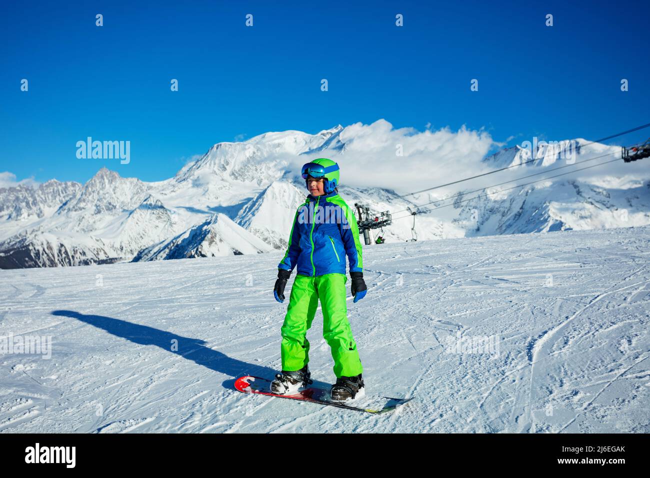 Garçon sur le snowboard dans un casque et un masque de tenue de snowboarder complet Banque D'Images