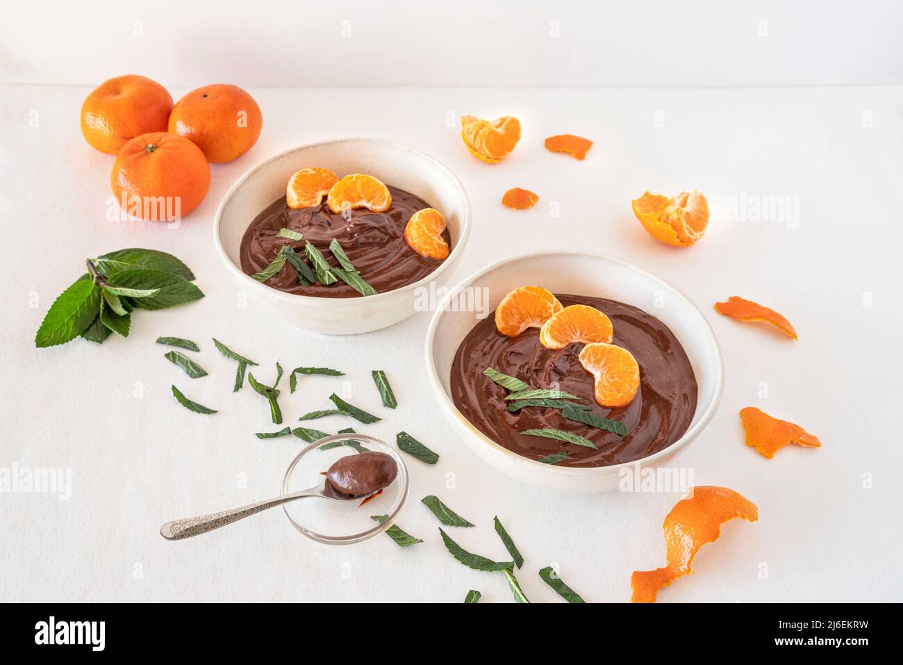 Crème au chocolat dans des bols avec des oranges et des feuilles de menthe Banque D'Images