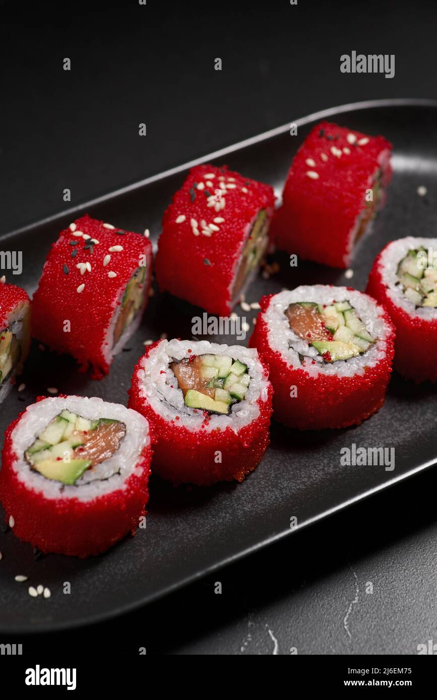 Un délicieux rouleau de sushis frais traditionnels sur fond noir. Sushi roulent avec du riz, du nori, du fromage à la crème, du tobiko caviar, de l'avocat. Menu sushi. Japane Banque D'Images