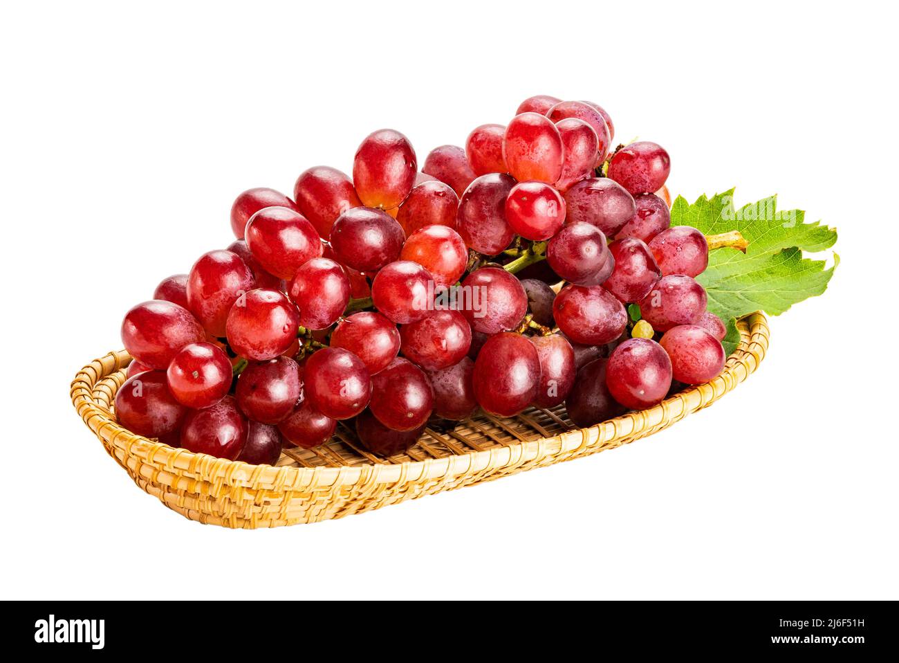 Bouquet de raisins rouges mûrs, raisins Crimson Seedless, avec feuille verte dans un plateau en bambou isolé sur fond blanc avec un chemin d'écrêtage. Banque D'Images