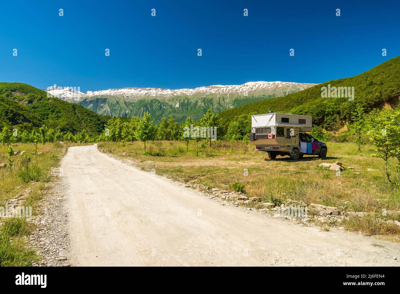 Petite fourgonnette de voyage camping est garée sous une immense formation de montagne. Tourisme vacances et voyages. Fourgonnette et paysage de montagnes Banque D'Images