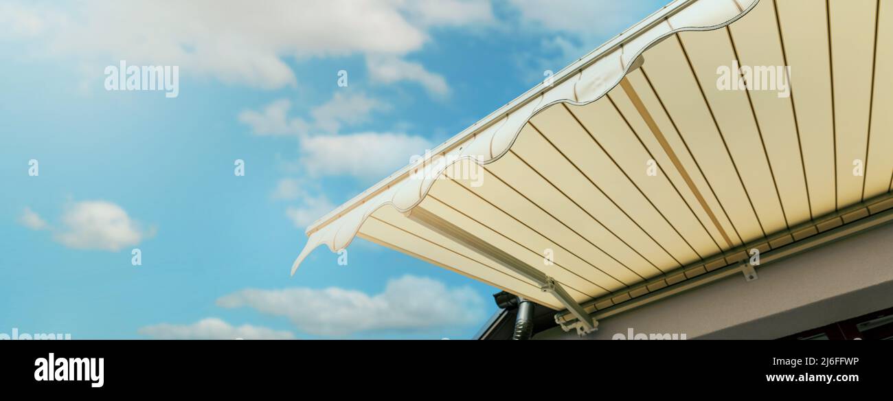 auvent rétractable installé sur le mur au-dessus de la fenêtre de la maison contre le ciel bleu. bannière avec espace de copie Banque D'Images