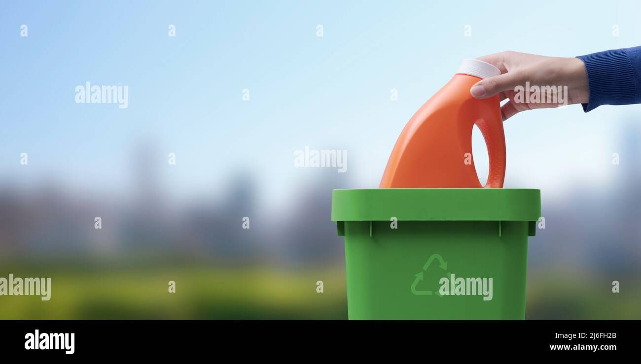 Femme mettant une bouteille de détergent en plastique dans la poubelle, concept de recyclage, paysage naturel en arrière-plan Banque D'Images