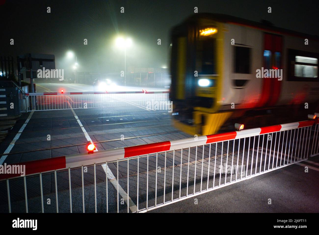 Un train en mouvement sur un passage à niveau automatique à Barmouth, dans le nord du pays de Galles, par une nuit brumeuse Banque D'Images