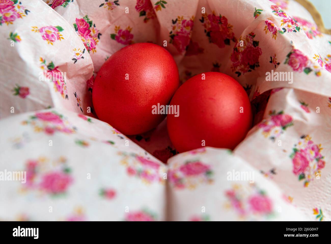 Deux œufs de Pâques teints en rouge dans un bol avec des serviettes en papier à fleurs. Banque D'Images