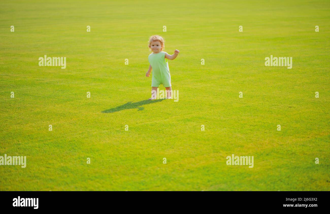 Mignon petit garçon drôle apprendre à ramper pas, ayant le plaisir de jouer sur la pelouse dans le jardin. Banque D'Images