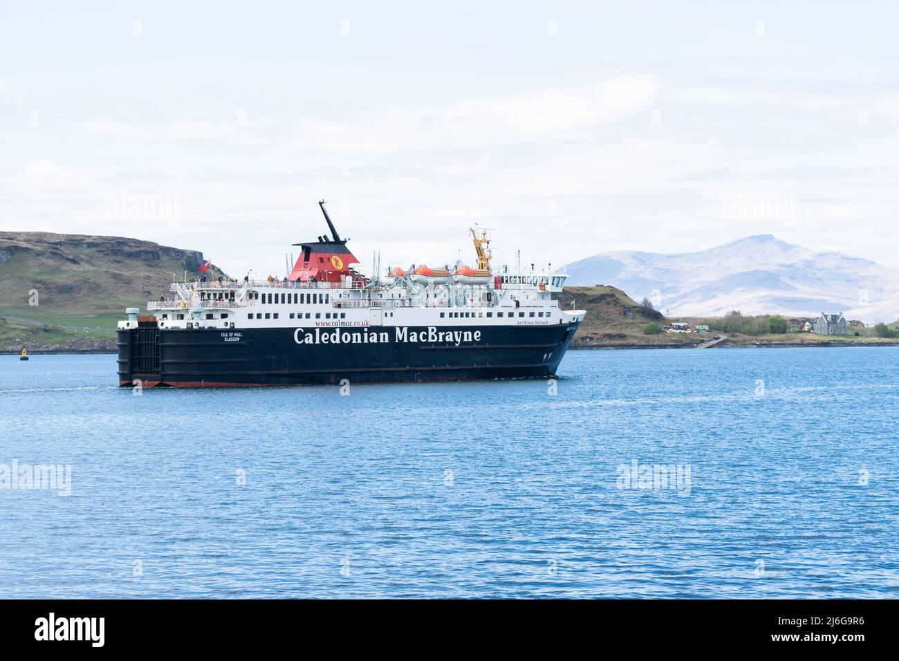Ferry Caledonian MacBrayne naviguant à travers les eaux côtières écossaises avec les hauts plateaux en arrière-plan Banque D'Images