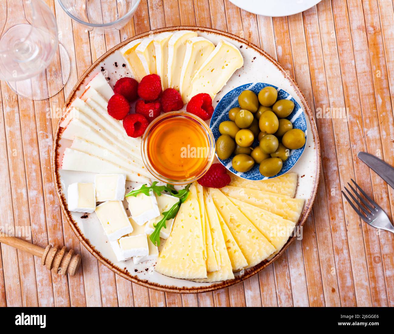 Assiette avec différents types de fromage, framboises et olives Banque D'Images