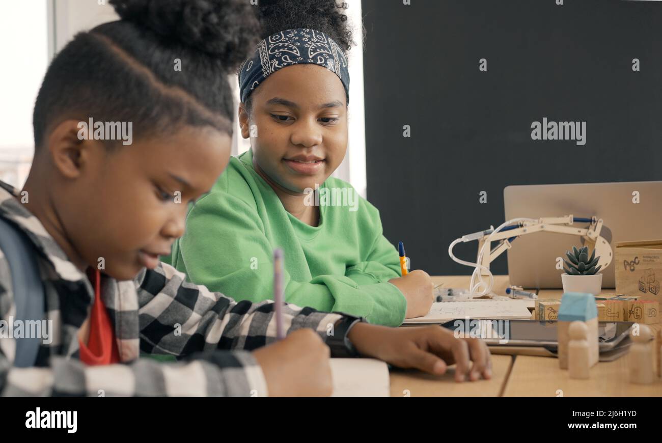 Étudiant en maternelle internationale écrivant un livre ensemble en classe d'école élémentaire, les élèves appréciant étudier en classe. Banque D'Images