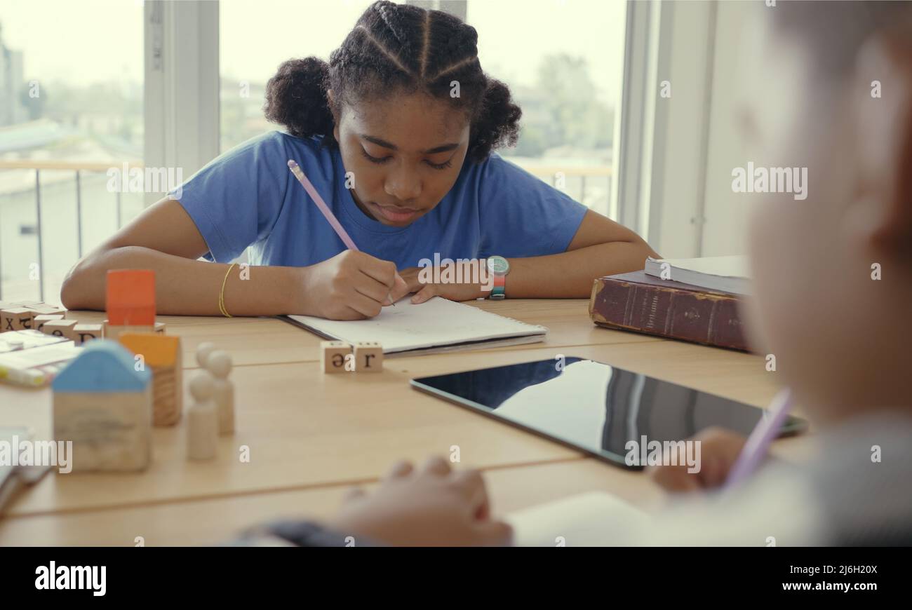 Étudiant en maternelle internationale écrivant un livre ensemble en classe d'école élémentaire, les élèves appréciant étudier en classe. Banque D'Images