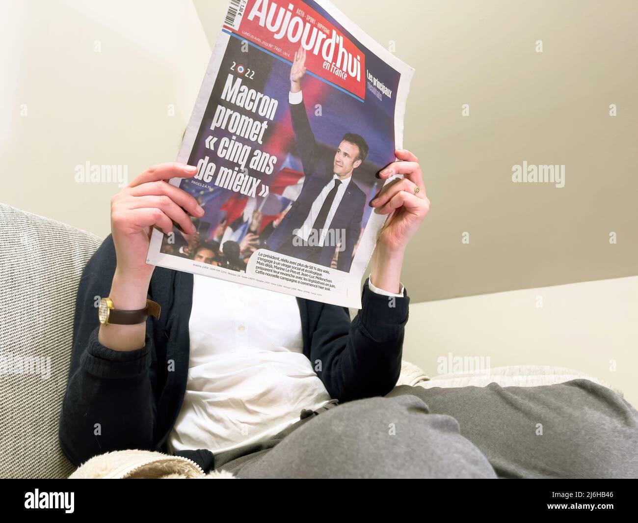 Paris, France - 25 avril 2022 : une femme lisant sur un canapé confortable le dernier journal Aujordd'hui, couverture avec le président français sortant Emmanuel Macron après avoir battu Marine le Pen pour un second mandat de cinq ans Banque D'Images