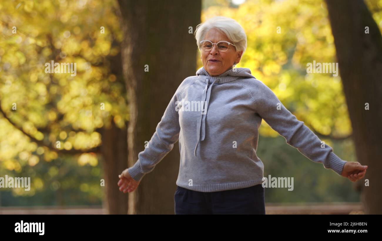Concept de fitness. Être physiquement actif dans la vieillesse paie. Photo extérieure de la femme de race blanche en jogging gris à capuche. Photo de haute qualité Banque D'Images