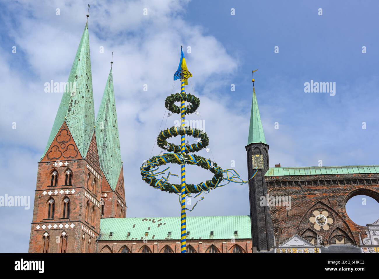 Maypole aux couleurs de l'Ukraine avec des colombes de paix entre les tours de la Lubeck Marienkirche et l'hôtel de ville contre un ciel bleu avec des nuages à GE Banque D'Images