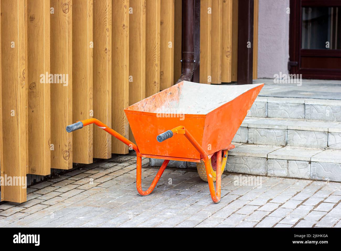 Chariot de brouette orange vif pour le jardinage et le chantier de construction sur la rue. Banque D'Images