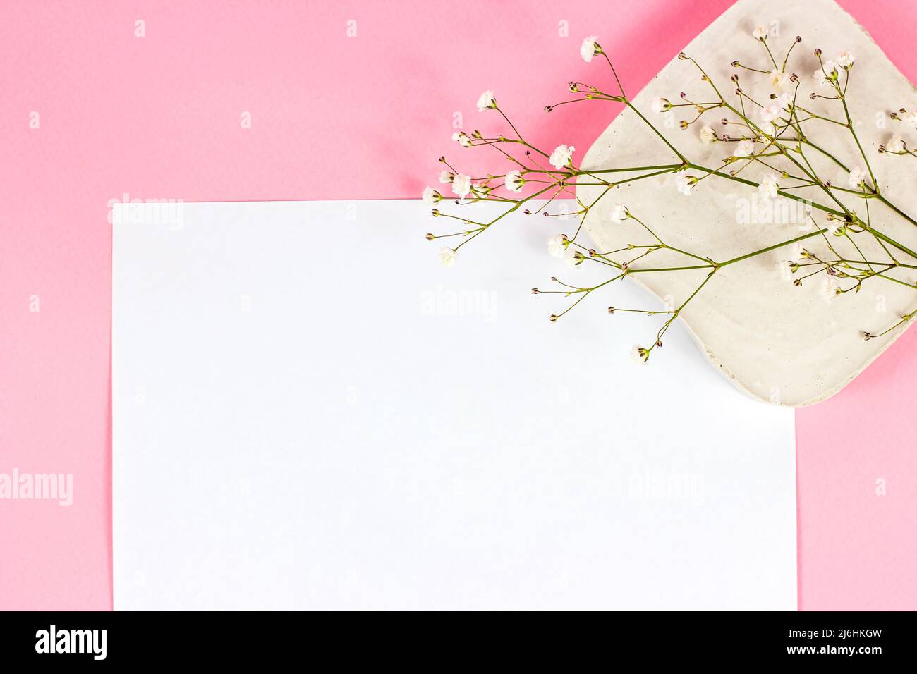 Page blanche vierge de bloc-notes avec espace de copie pour le texte avec de petites fleurs sur fond rose pastel vue du dessus. Maquette de papier de mariage vide, valent romantique Banque D'Images