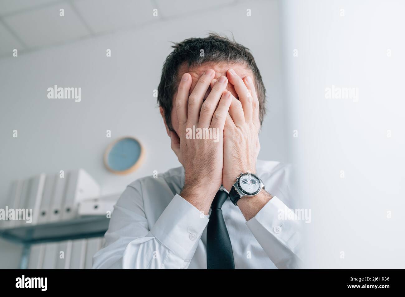 Faillite commerciale, homme d'affaires couvrant la face avec les mains et pleurant au bureau, attention sélective Banque D'Images