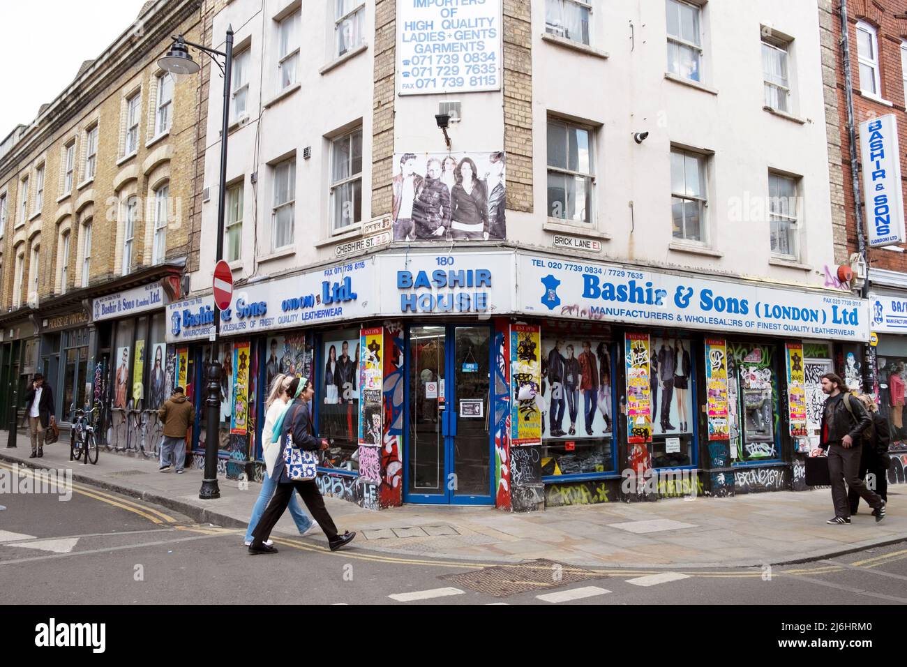 Les gens qui marchent devant Bashir House (Bashir & Sons) magasin pakistanais au coin de la rue dans Brick Lane East London E1, Angleterre KATHY DEWITT Royaume-Uni Banque D'Images