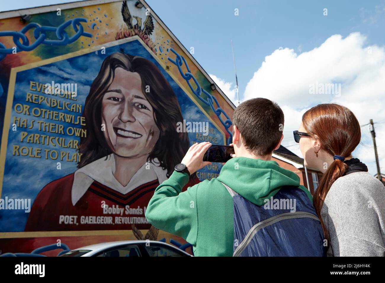 Couple touristique d'Espagne Prenez des photos à la fresque de Bobby Sands sur le mur du bureau de Sinn Fein, Lower Falls Road, West Belfast, Irlande du Nord, Banque D'Images