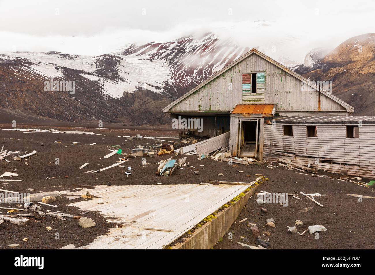 des montagnes enneigées et des bâtiments délabrés de la chasse à la baleine abandonnée et de la station scientifique de l'île de tromperie antarctique Banque D'Images