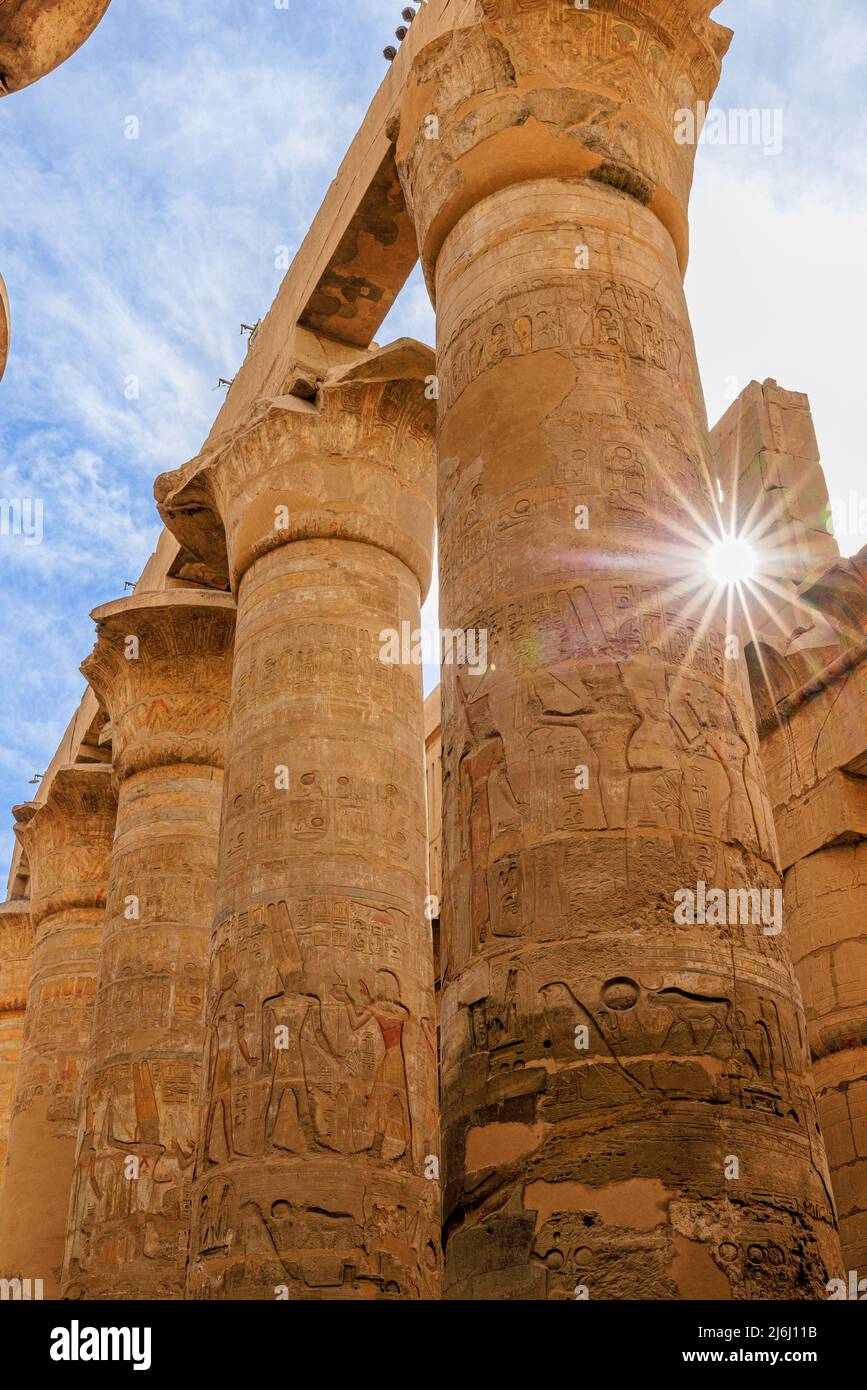 un coucher de soleil entre les colonnes sculptées avec des hiéroglyphes dans le grand hall hypostyle du temple de karnak en égypte louxor Banque D'Images