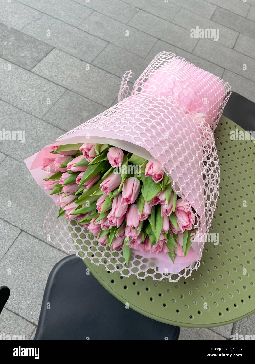 Grand bouquet de printemps de tulipsin rose emballage sur table de café. Banque D'Images