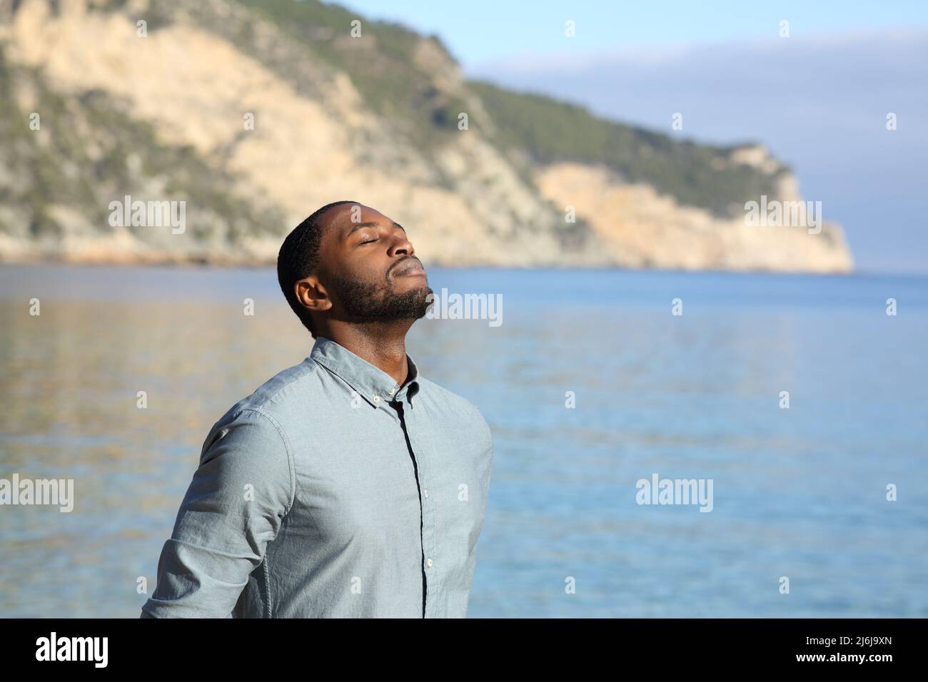 Homme à la peau noire se détendant et respirant de l'air frais sur la plage Banque D'Images
