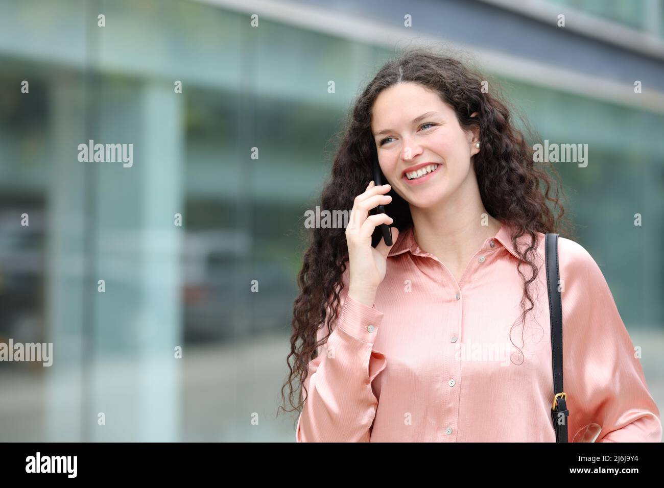 Bonne femme élégante parlant sur un téléphone intelligent marchant dans la rue Banque D'Images