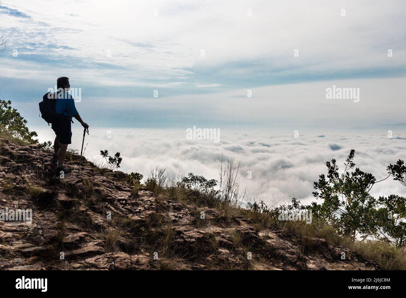 Randonneur asiatique en silhouette debout au sommet de la montagne en admirant le paysage de nuages et le lever du soleil Banque D'Images