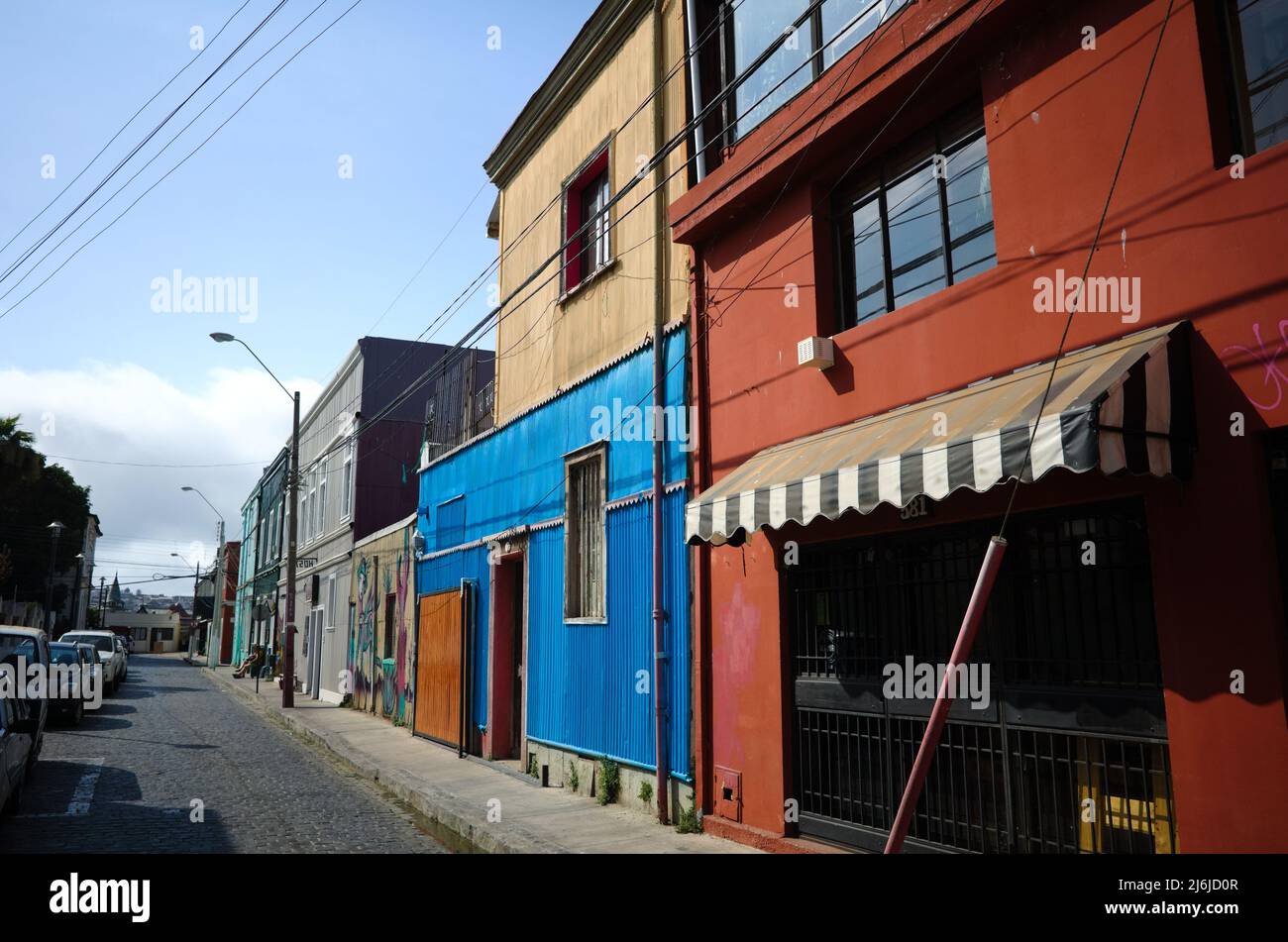 Valparaiso, Chili - février 2020 : maisons multicolores de deux étages dans l'un des quartiers de la ville sur la colline. Rue pavée dans la vieille ville avec des voitures garées Banque D'Images