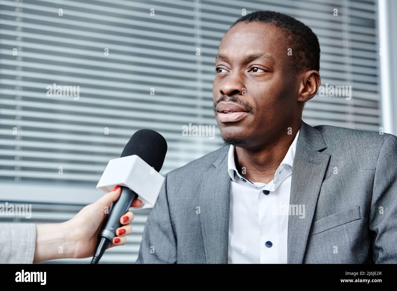 Portrait d'un expert d'affaires afro-américain parlant au microphone tout en donnant l'interivew en studio Banque D'Images