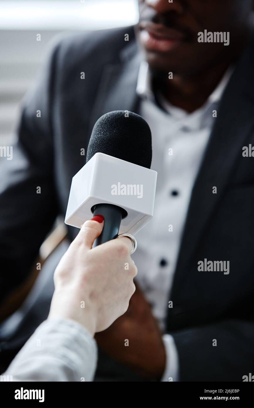 Gros plan vertical d'une jeune femme tenant un microphone tout en interviewant un expert Banque D'Images