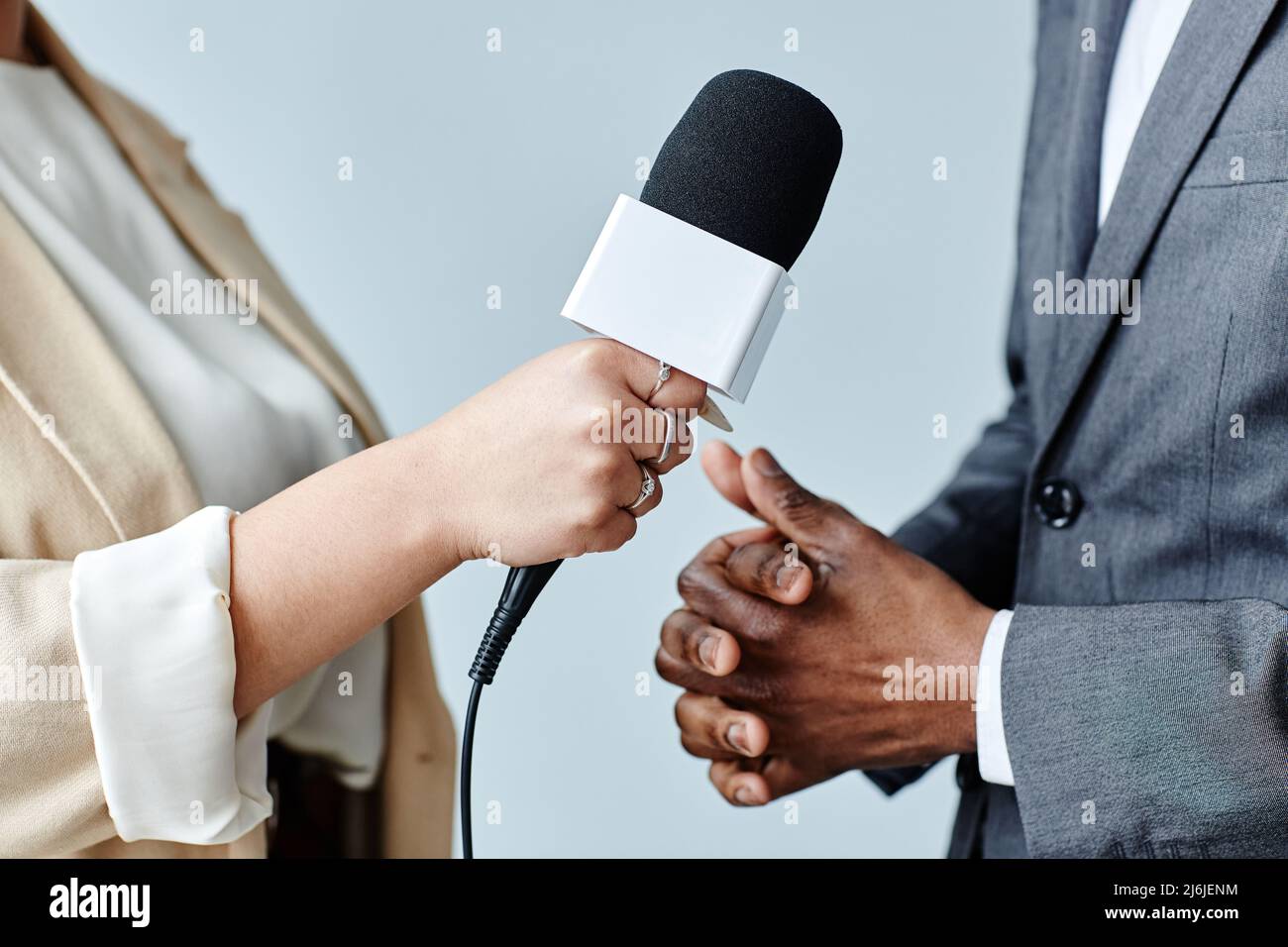 Vue de côté d'une jeune femme tenant un microphone tout en interviewant un expert en affaires Banque D'Images