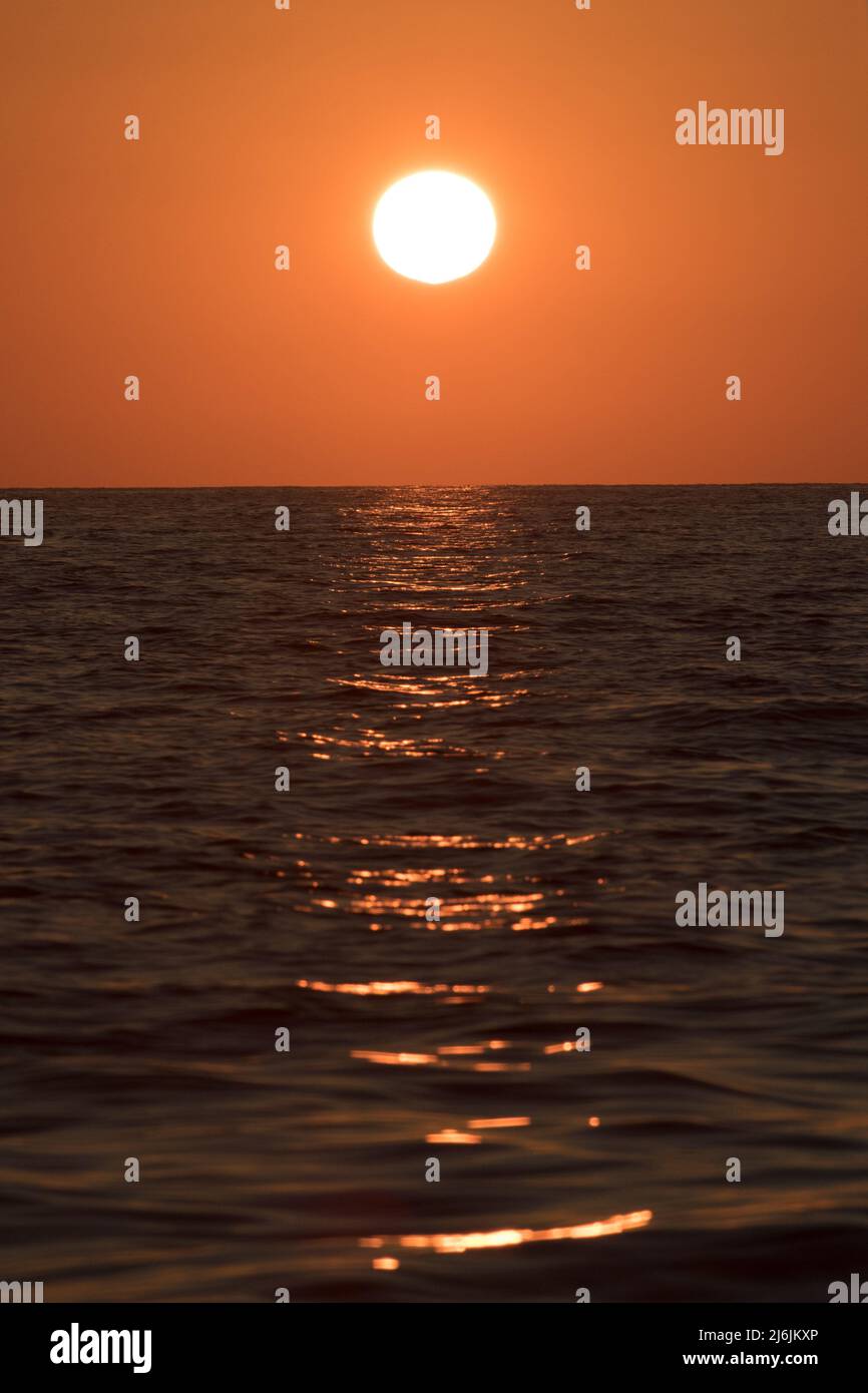 Le soleil circulaire se couche sur une autre soirée d'été sereine au-dessus de la mer Méditerranée calme dans l'île des Baléares d'Ibiza Banque D'Images