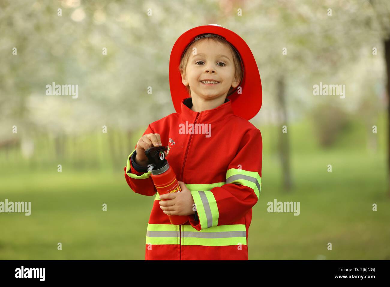 Petit enfant avec costume de pompier dans le parc, prétendant être un vrai pompier, jouant au coucher du soleil Banque D'Images
