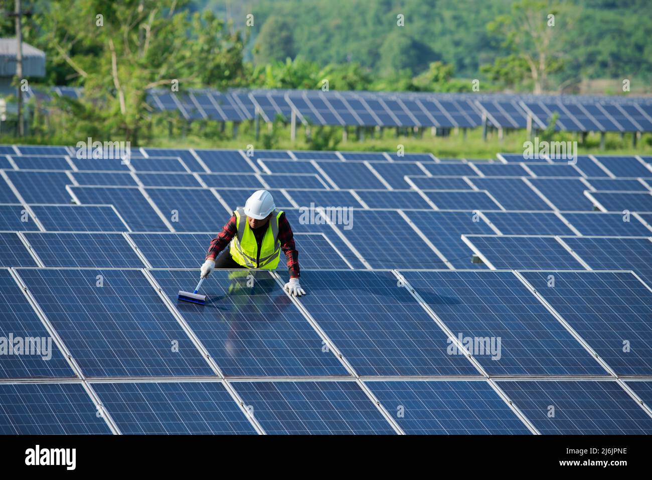 Nettoyage des panneaux solaires par les travailleurs en sécurité uniforme à la ferme solaire Banque D'Images