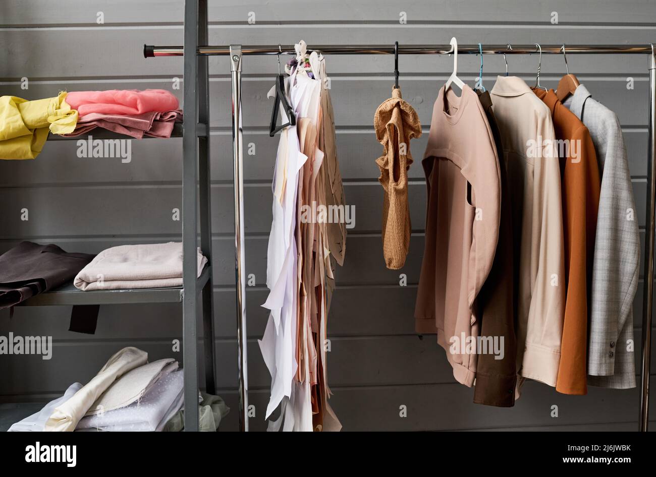 Partie d'un long rack avec variété de vêtements décontractés de différentes couleurs suspendus dans une boutique moderne ou atelier de tailleur ou de mode designer Banque D'Images