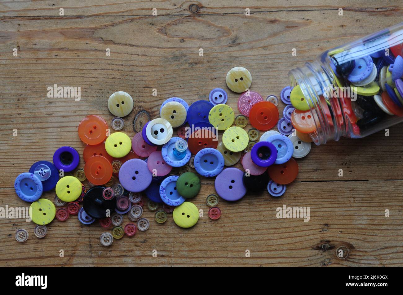 Une collection de boutons colorés se déverse dans un pot de rangement prêt  pour un projet de couture ou de mending Photo Stock - Alamy