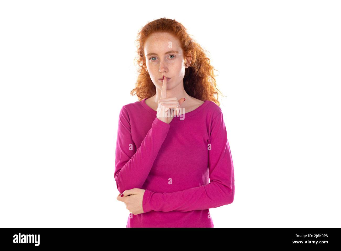 Photo de femme ravie réfléchie, imagine quelque chose, a des cheveux naturels de gingembre ondulé, porte un t-shirt rose décontracté, se tient contre le mur blanc de studio, co Banque D'Images