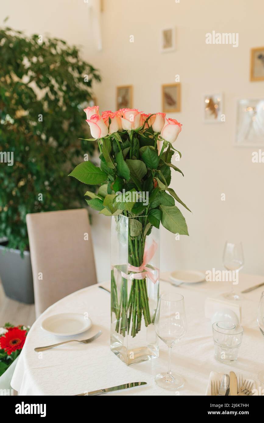 Un bouquet de belles roses roses blanches dans un vase en verre sur la table de banquet Banque D'Images