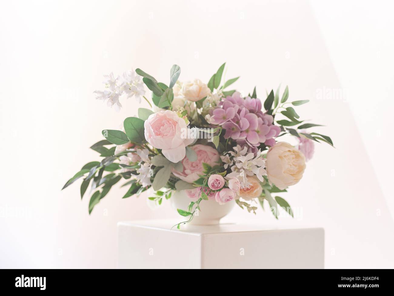 Une composition de différentes fleurs dans un vase blanc sur un podium carré. Le concept d'un fleuriste. Un beau bouquet fraîchement coupé. Livraison de fleurs. Photo de haute qualité Banque D'Images Une composition de différentes fleurs dans un vase blanc sur un podium carré. Le concept d'un fleuriste. Un beau bouquet fraîchement coupé. Livraison de fleurs. Photo de haute qualité Banque D'Images