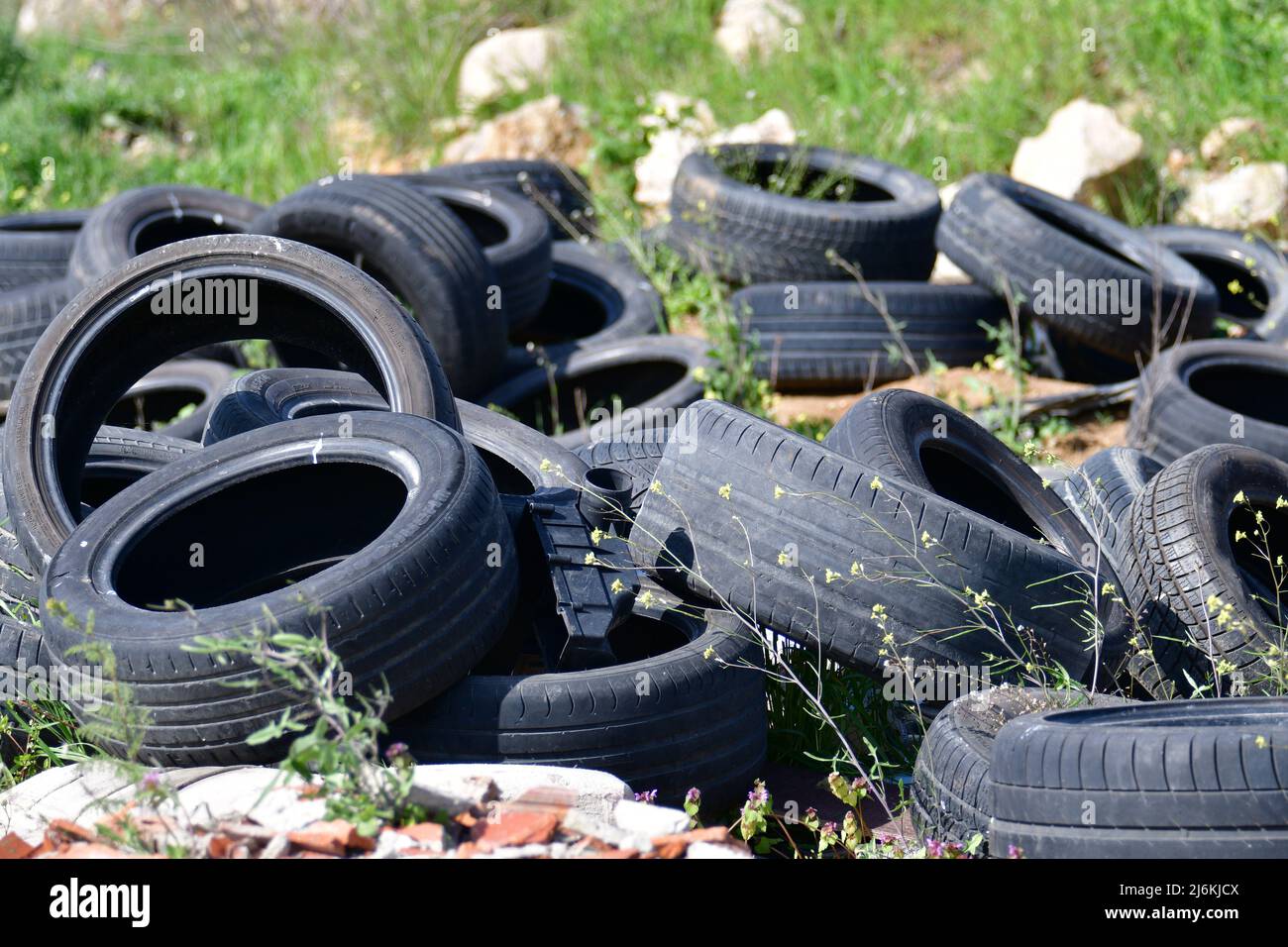 Pile de vieux pneus de voiture en caoutchouc éparpillés dans le champ Banque D'Images