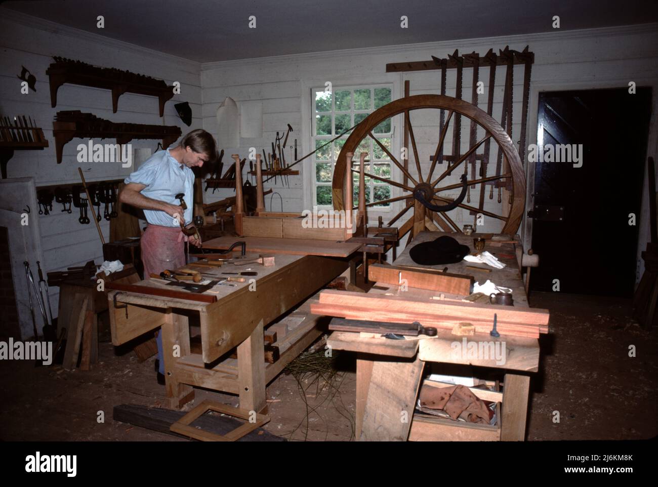 Williamsburg, Virginie. ÉTATS-UNIS 9/1987. Wheelwright a fait des roues pour la plupart de tout ce qui a ‘roulé’ dans Colonial Williamsburg. Des roues fabriquées à la main étaient nécessaires pour les routes de terre et les routes en briques ou en pavés, et assez solides pour supporter des tonnes de produits, de céréales, de tabac, de coton, de bétail et de canon militaire. Banque D'Images