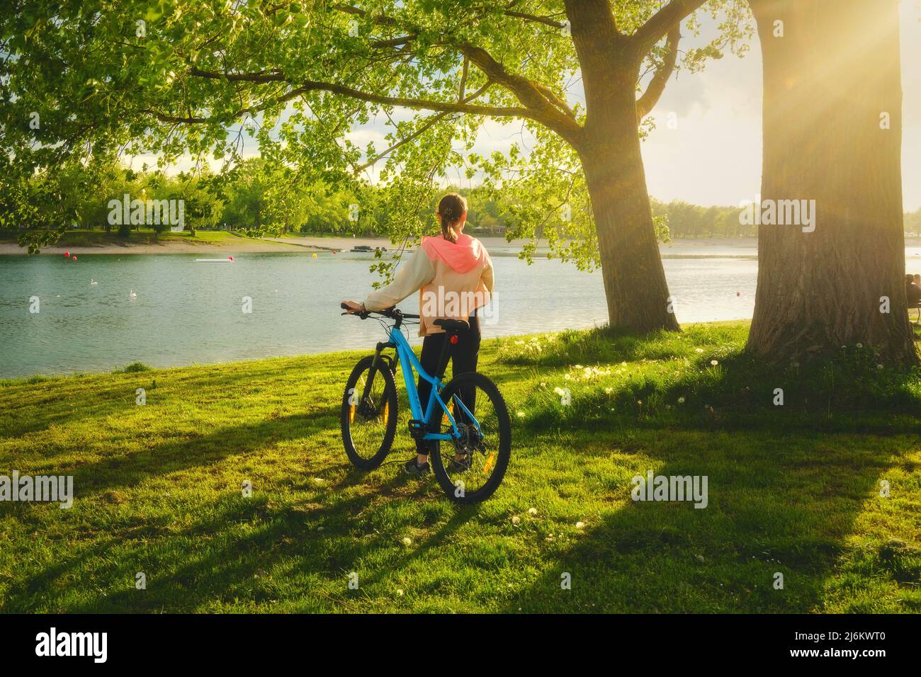 Femme à vélo de montagne près du lac au coucher du soleil en été Banque D'Images