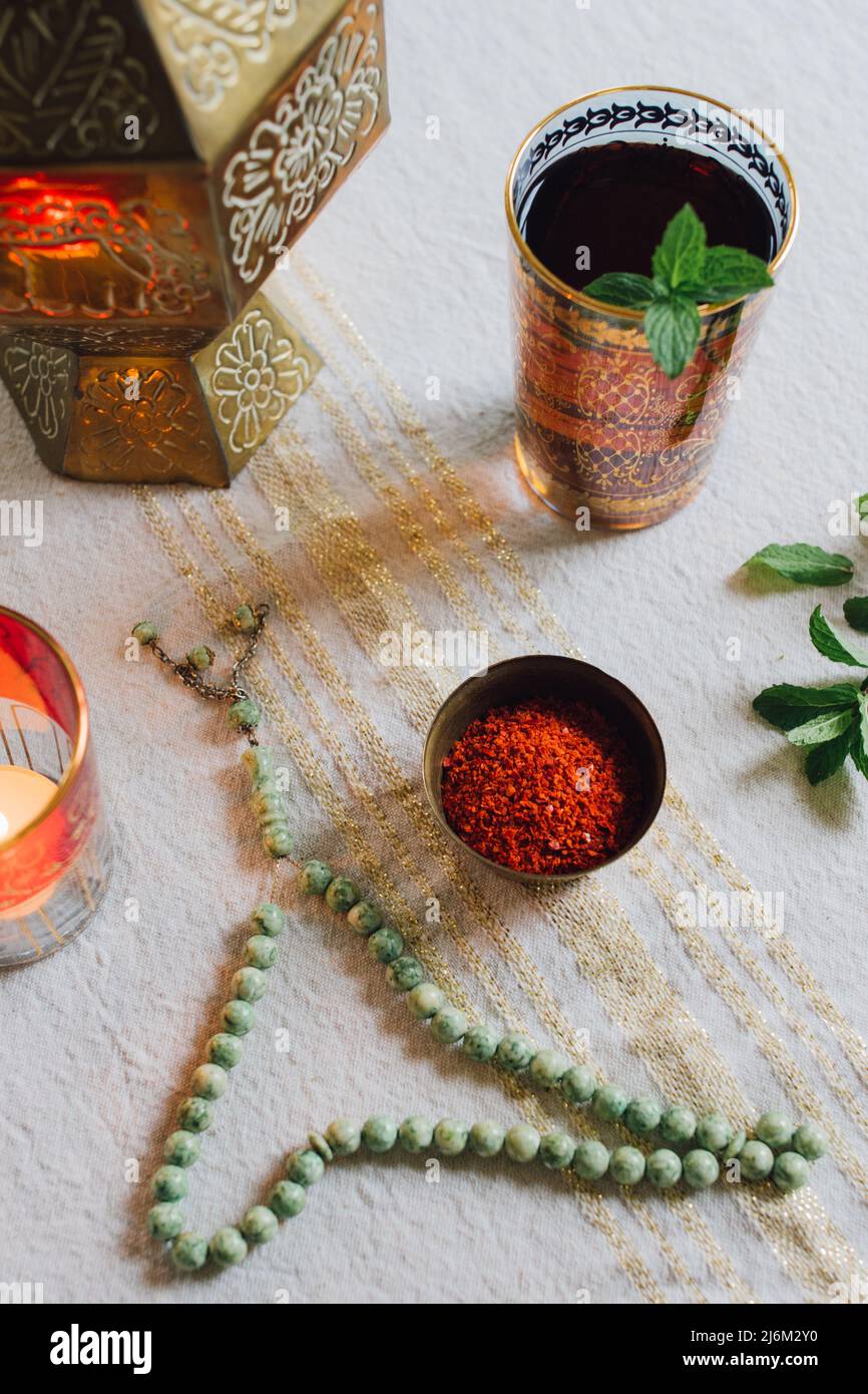 Table avec tissu doré, flocons de piment Alep dans le plat, bougie chauffe-plat, perles de prière de jade, thé à la menthe Banque D'Images