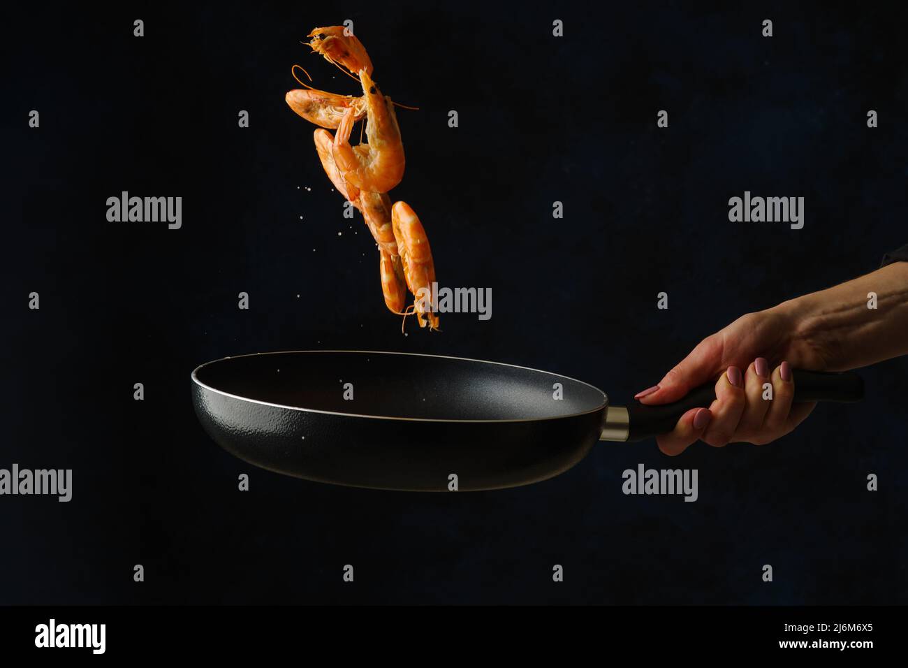 Des crevettes géantes dans une poêle en vol gelé sur fond noir. Alimentation gastronomique végétarienne saine, mode de vie sain. Fruits de mer. Recettes pour le restaurant an Banque D'Images