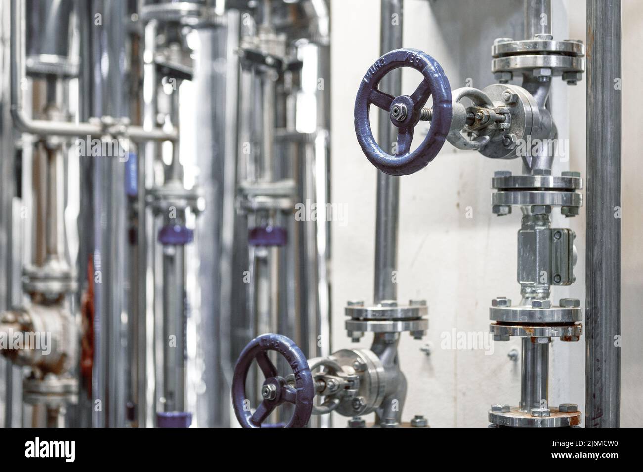Tuyaux métalliques fins avec petites vannes bleues et brides à l'usine Banque D'Images